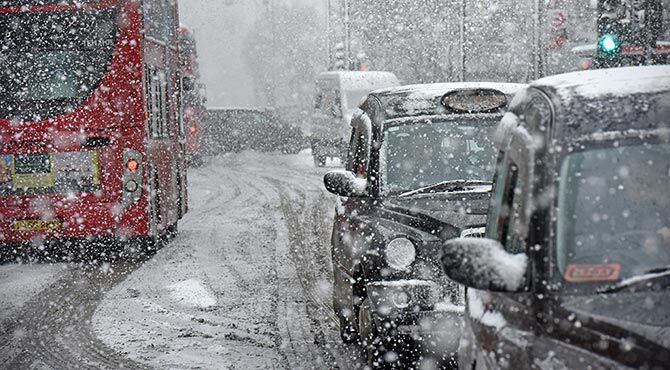 Snowstorm in London's Oxford Street. Image shows a several black cabs, a red London bus and a snowy street.